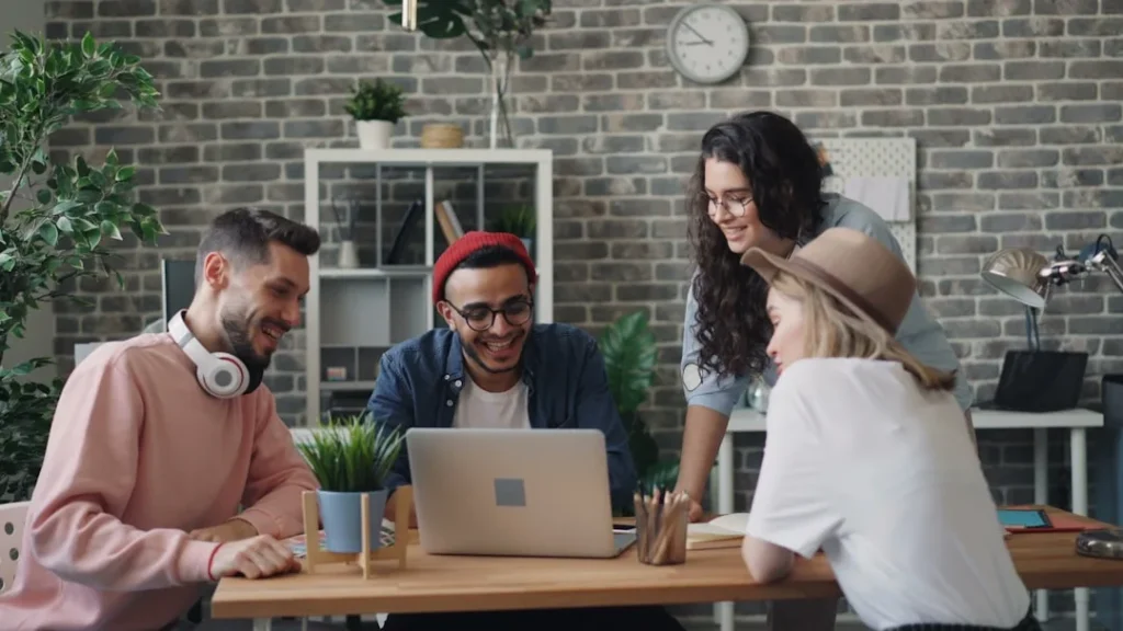 a group of people sitting around a table with a laptop