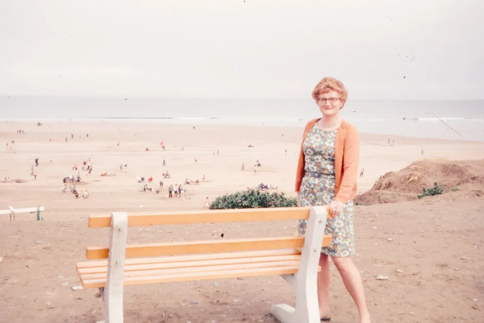 Woman standing by a bench overlooking a crowded beach