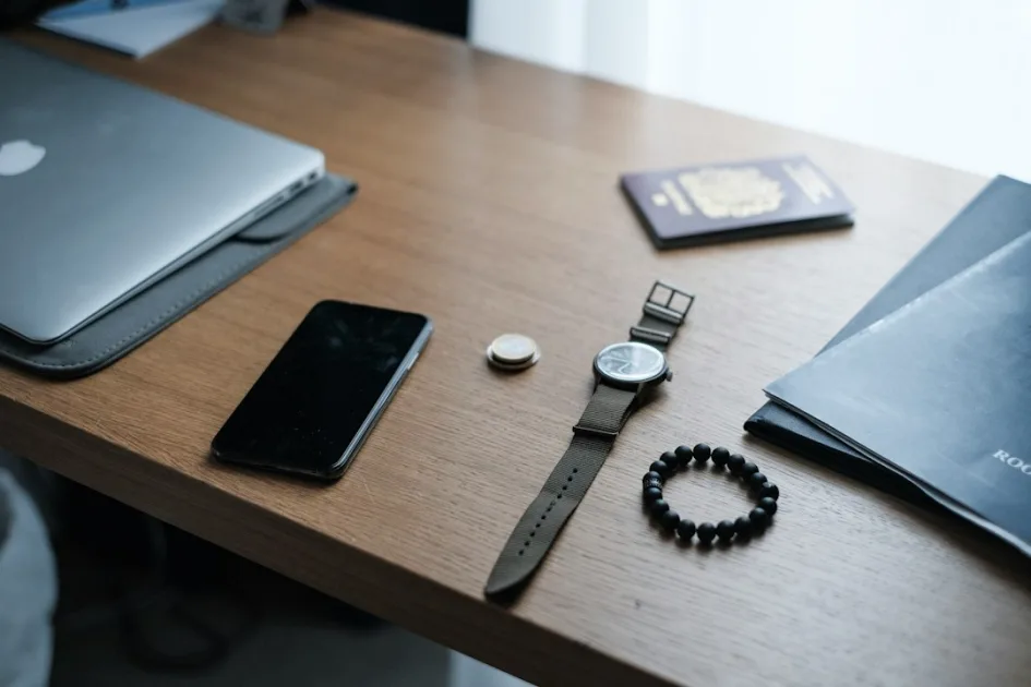 black smartphone and round black wristwatch on top of brown desk