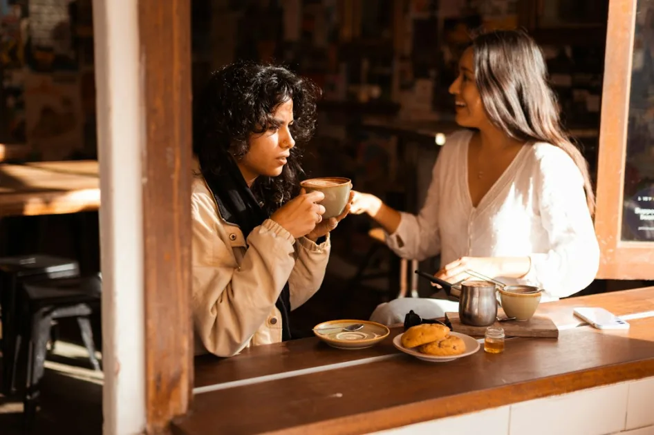 A couple of women sitting at a table with cups of coffee