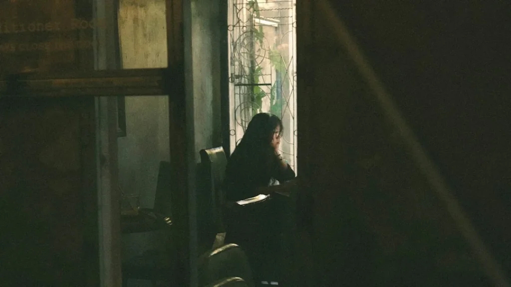 A woman in black looks out a window